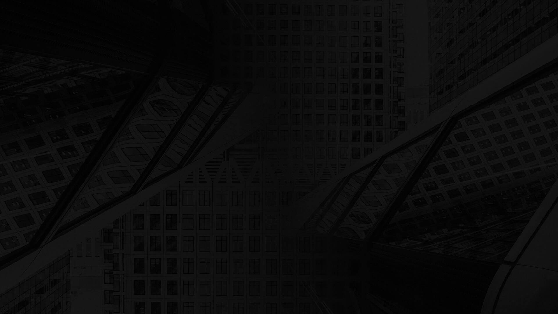 Low-angle black-and-white view of intersecting glass skyscrapers with grid-pattern facades and reflective surfaces.